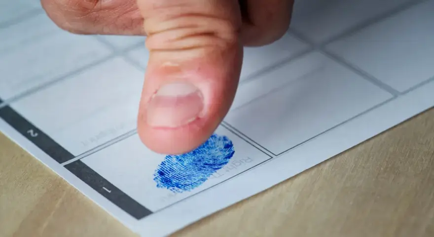 Kciuk z niebieskim odciskiem palca na papierze. Czy to początek śledztwa, czy tylko rutynowa procedura? Jak długo można być podejrzanym?