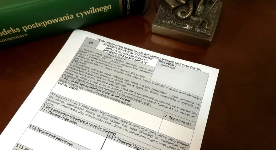 Dokument z pouczeniami do wypełnienia sprzeciwu od wyroku zaocznego lub nakazu zapłaty, obok zielonej księgi "Kodeks postępowania cywilnego".