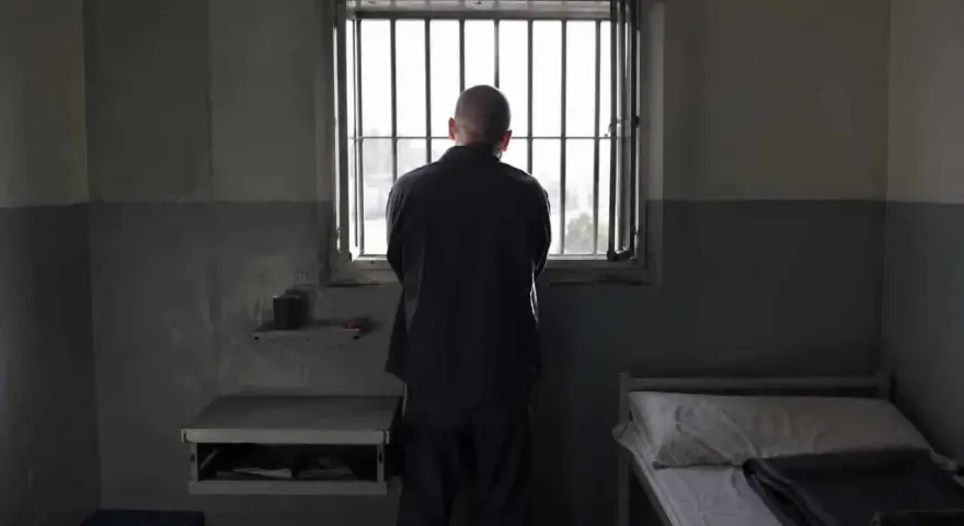 Samotny więzień patrzy przez kraty okna. To obraz odzwierciedlający cele wykonywania kary pozbawienia wolności: izolację i refleksję.