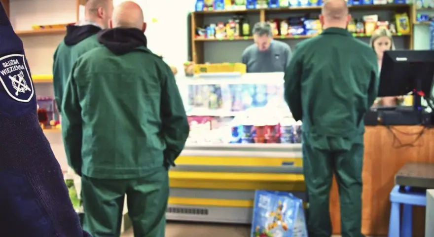 Strażnicy więzienni w zielonych uniformach robią zakupy w więziennej kantynie.