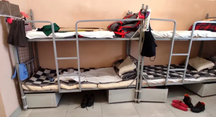 Tak wygląda dzień w areszcie śledczym: piętrowe łóżka, koce, poduszki i buty na podłodze.