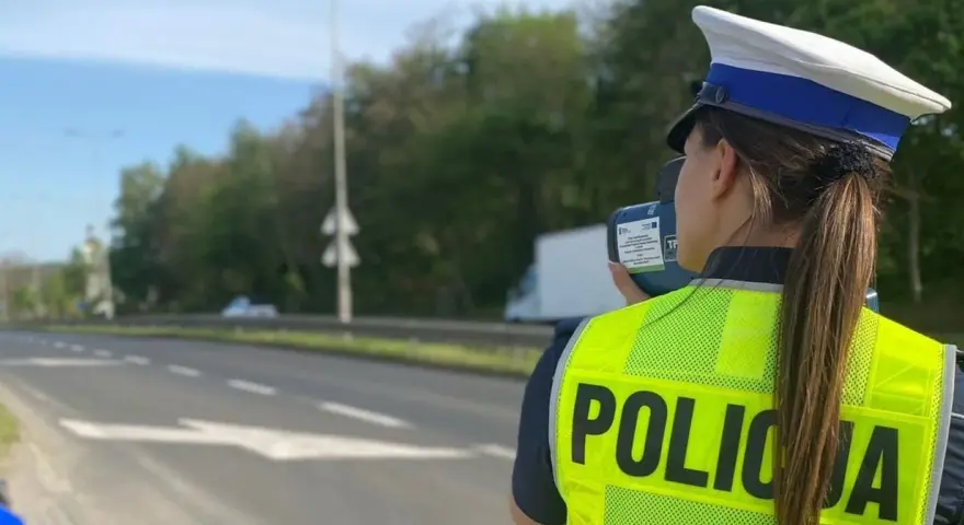 Policjantka w kamizelce odblaskowej mierzy prędkość pojazdów. Uważaj na tryb przyspieszony na drodze!