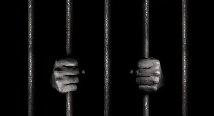 Dwie dłonie zaciskają się na zimnych prętach więziennych. Czy to jego pierwszy raz, czy już recydywista penitencjarny?
