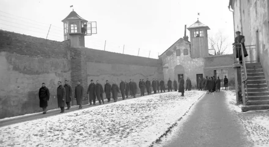 Więźniowie w mroźny dzień na dziedzińcu jednego z najcięższych więzień w Polsce. Strażnicy obserwują z wieżyczek.