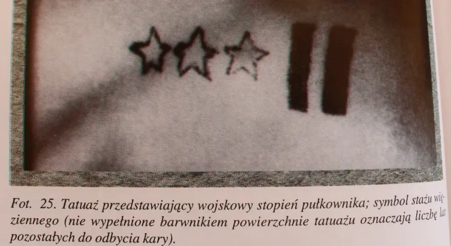 Trzy gwiazdy i dwie pionowe kreski – tatuaże więzienne, symbolizujące stopień wojskowy i czas pozostały do odbycia kary.