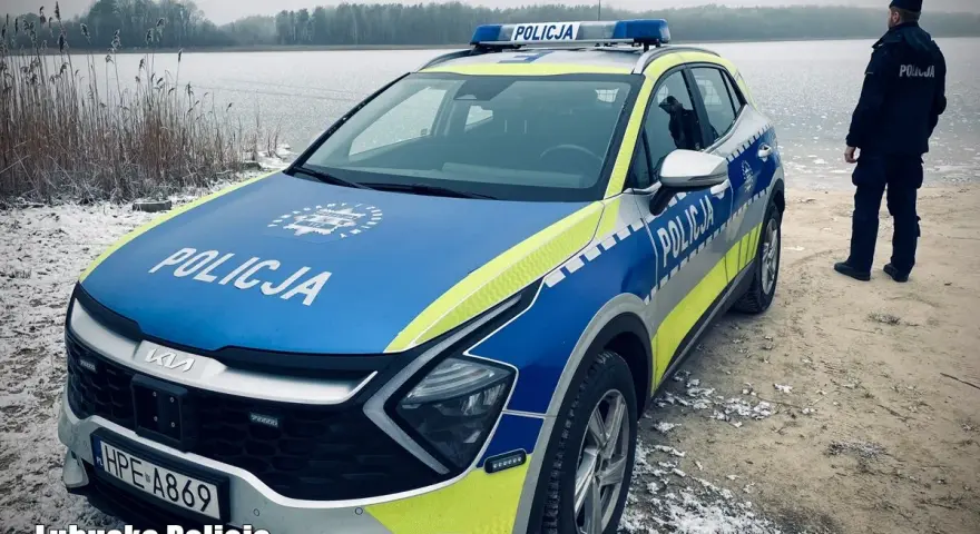 Policyjna lodówka stoi nad zamarzniętym jeziorem. Policjant w mundurze obserwuje okolicę.