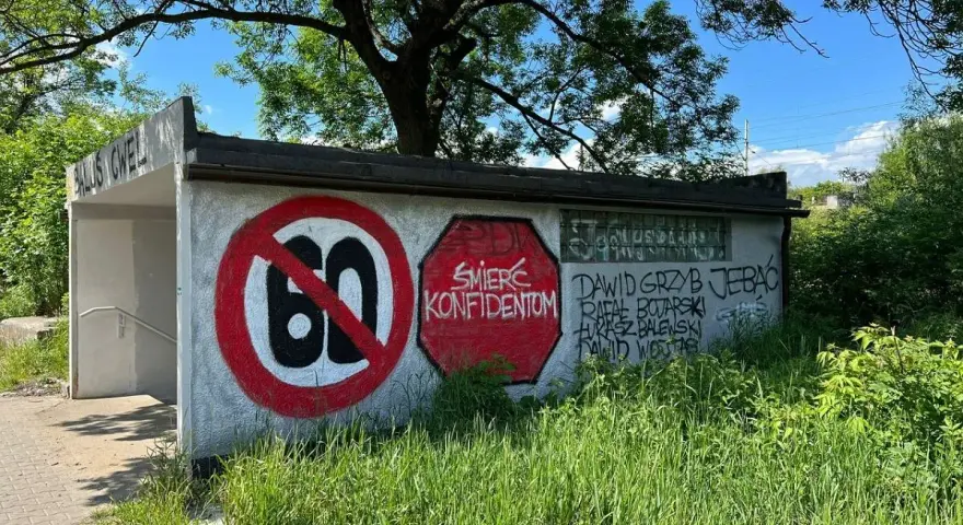 Niedziela, dzień cwel, pod drzewem, z zakazem 60 i napisami na ścianie.