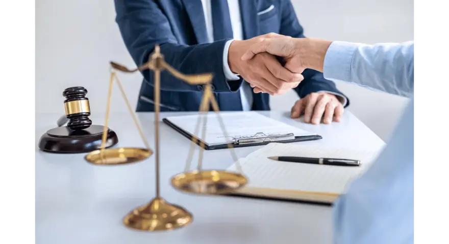 Uścisk dłoni prawników przy biurku z wagą sprawiedliwości i młotkiem. Sprawa 157 kk zakończona sukcesem.