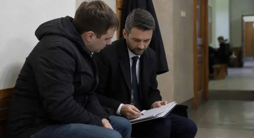 Prawnik omawia z klientem dokumenty dotyczące dobrowolnego poddania się karze a warunkowego umorzenia postępowania.