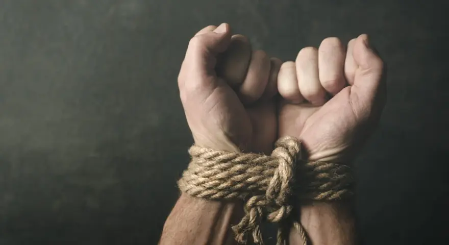 Związane dłonie, symbolizujące bezsilność i potencjalne naruszenie art. 189a kk.