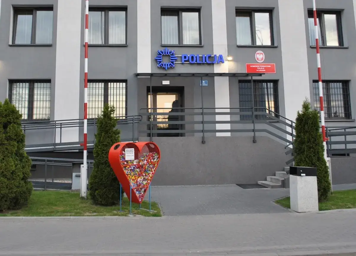 Przed budynkiem policji stoi serce-pojemnik na nakrętki. Nie ma informacji o godzinach dozoru policyjnego.
