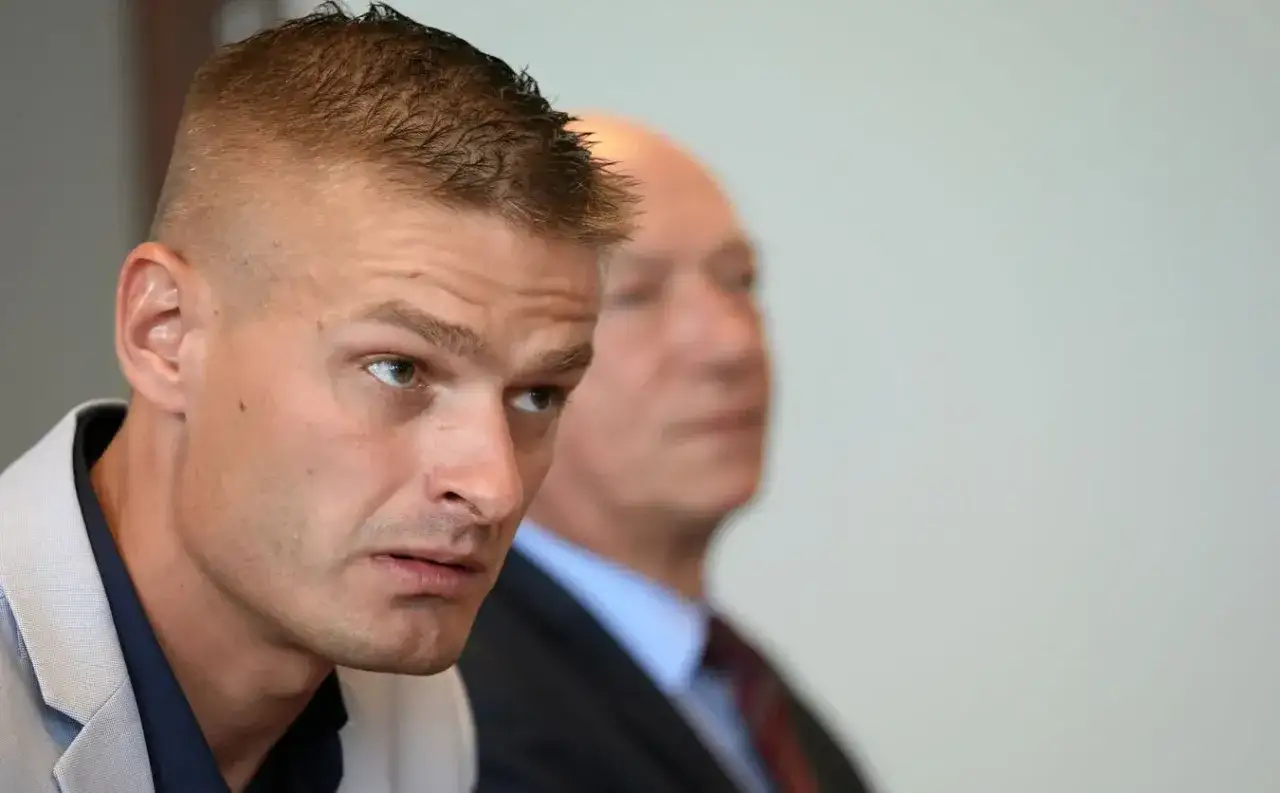 Tomasz Komenda w skupieniu słucha, gdy obok siedzi starszy mężczyzna w garniturze. Sprawa Tomasza Komendy budzi emocje.