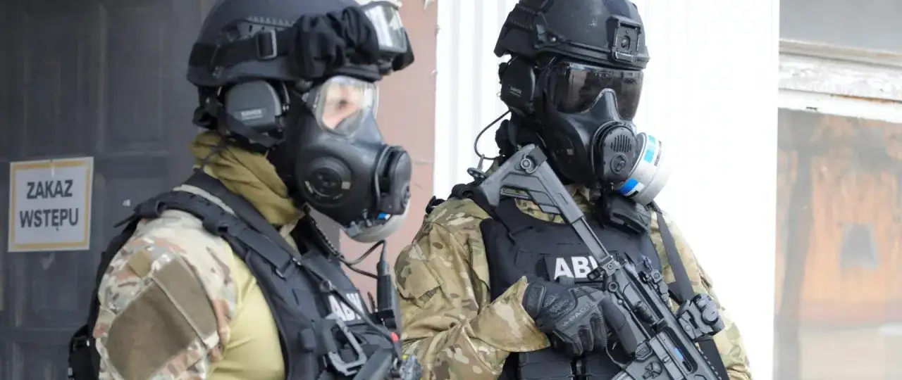Dw&oacute;ch funkcjonariuszy ABW w maskach gazowych i kamizelkach taktycznych, gotowych do akcji.
