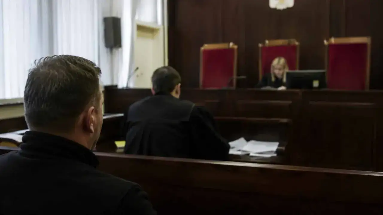 W sali sądowej mężczyzna w czerni czeka na wyrok. Sędzia w todze pochyla się nad dokumentami. Czy to oznacza kasację?