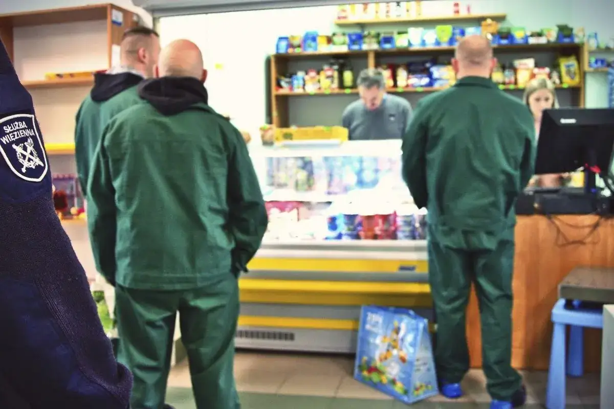 Strażnicy więzienni w zielonych uniformach robią zakupy w więziennej kantynie.