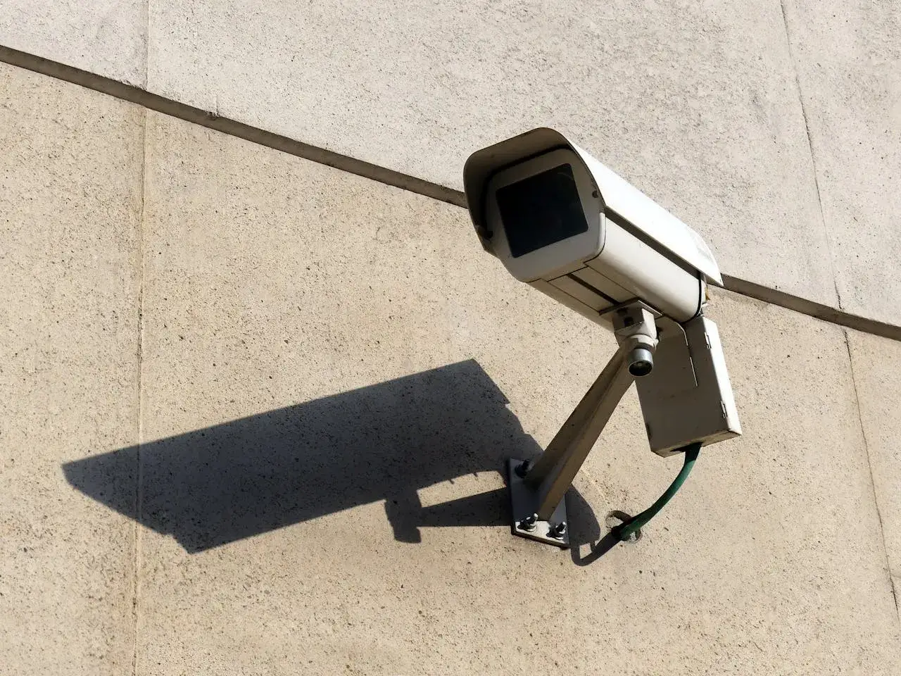 Kamera monitoringu na ścianie budynku. Taki dozór elektroniczny może być elementem bezpieczeństwa przy wynajem mieszkania.