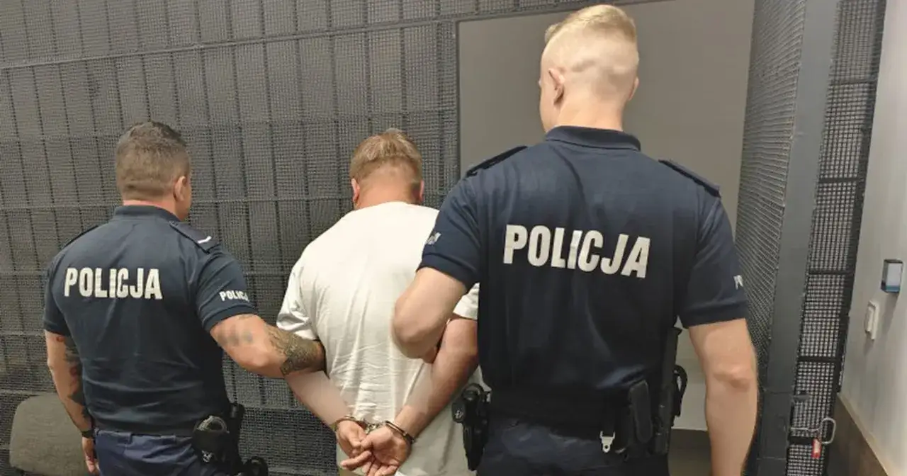 Dw&oacute;ch policjant&oacute;w w mundurach eskortuje zatrzymanego mężczyznę w kajdankach. To obrazuje, jak sprawdzić czy ktoś został zatrzymany przez policję.