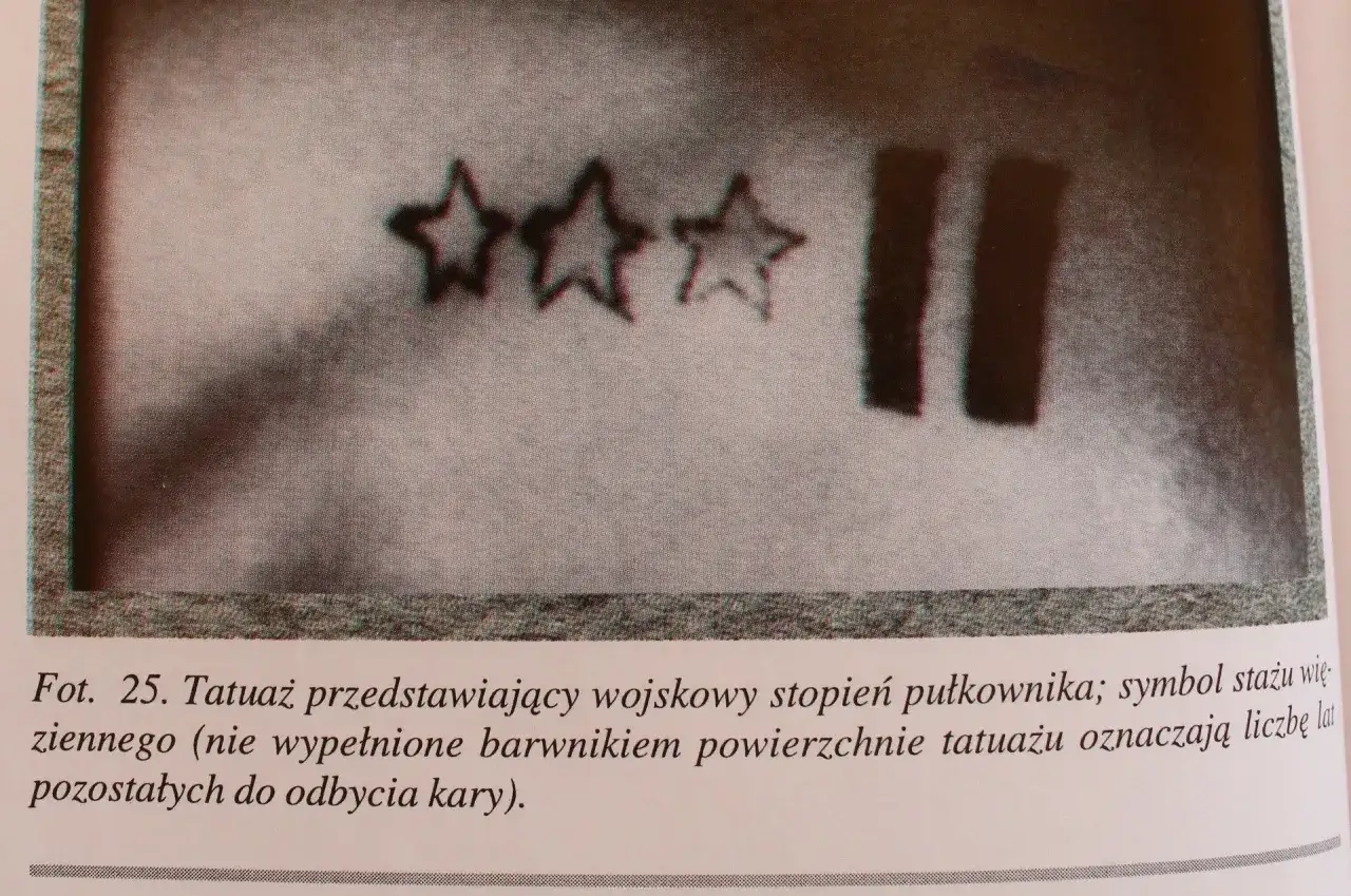 Tatuaże więzienne: trzy gwiazdy i dwie pionowe kreski, symbolizujące stopień wojskowy i lata kary.