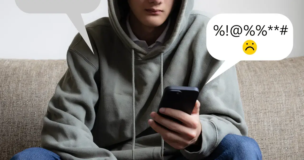 Młody człowiek w bluzie z kapturem trzyma smartfon. Dymek z tekstem zawiera symbole i smutną buźkę, sugerując pytanie: czy nagranie z telefonu może być dowodem w sprawie karnej?