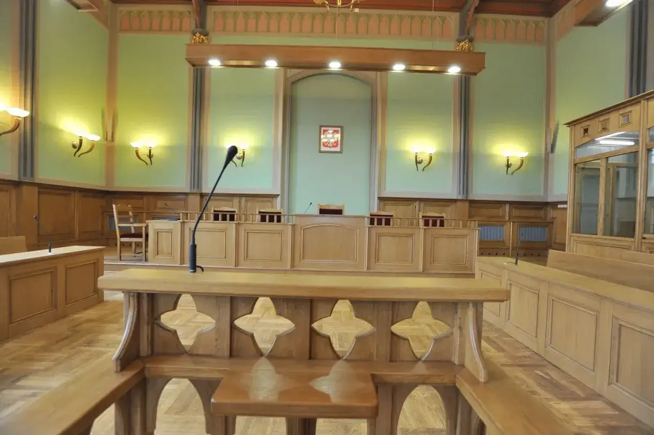 Wnętrze sali sądowej z drewnianymi ławami i mównicą. Tu zapadały decyzje, jakby wydawano list żelazny.