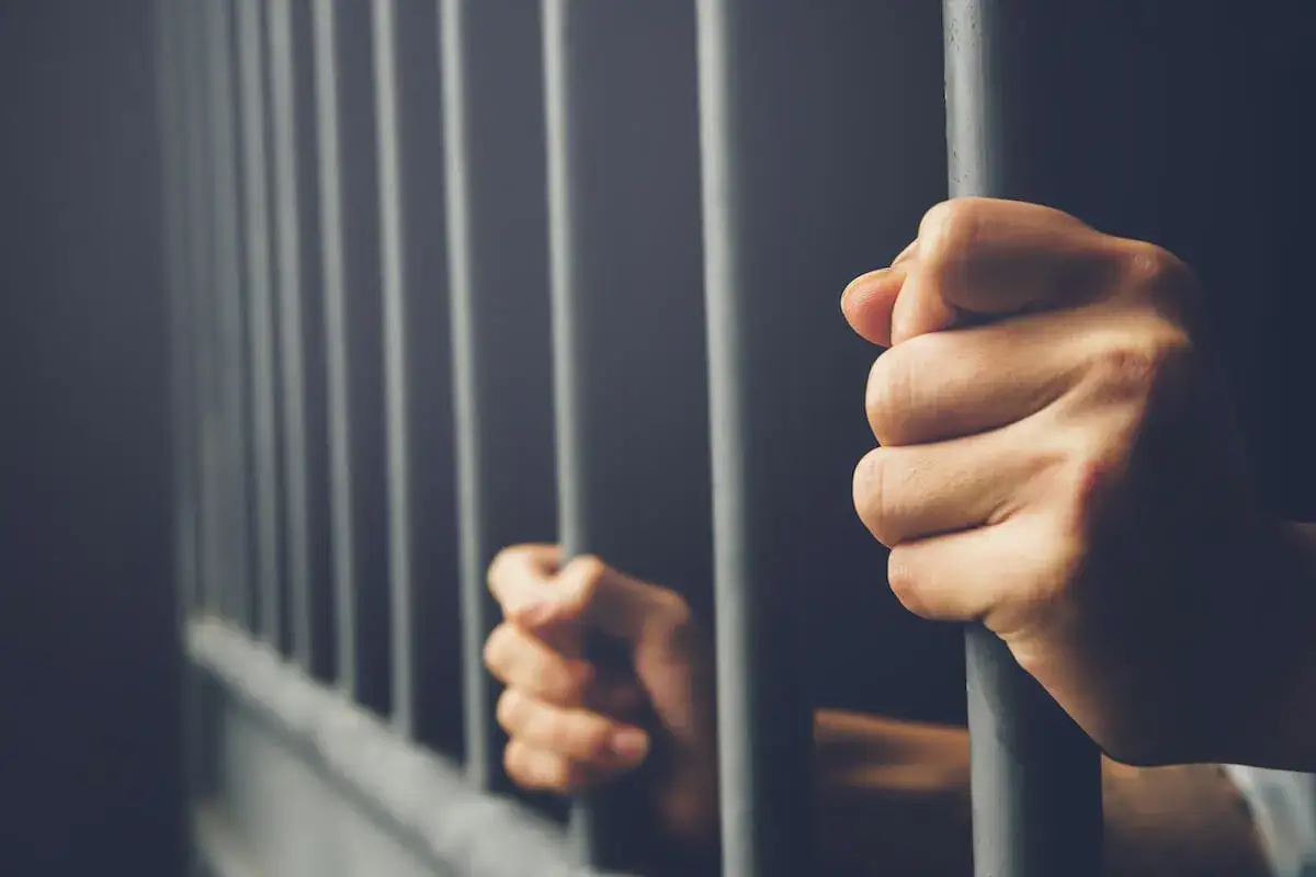 Dłoń zaciska się na kratach więzienia. Czy wyrok łączny a kara odbytą wpłyną na przyszłość?