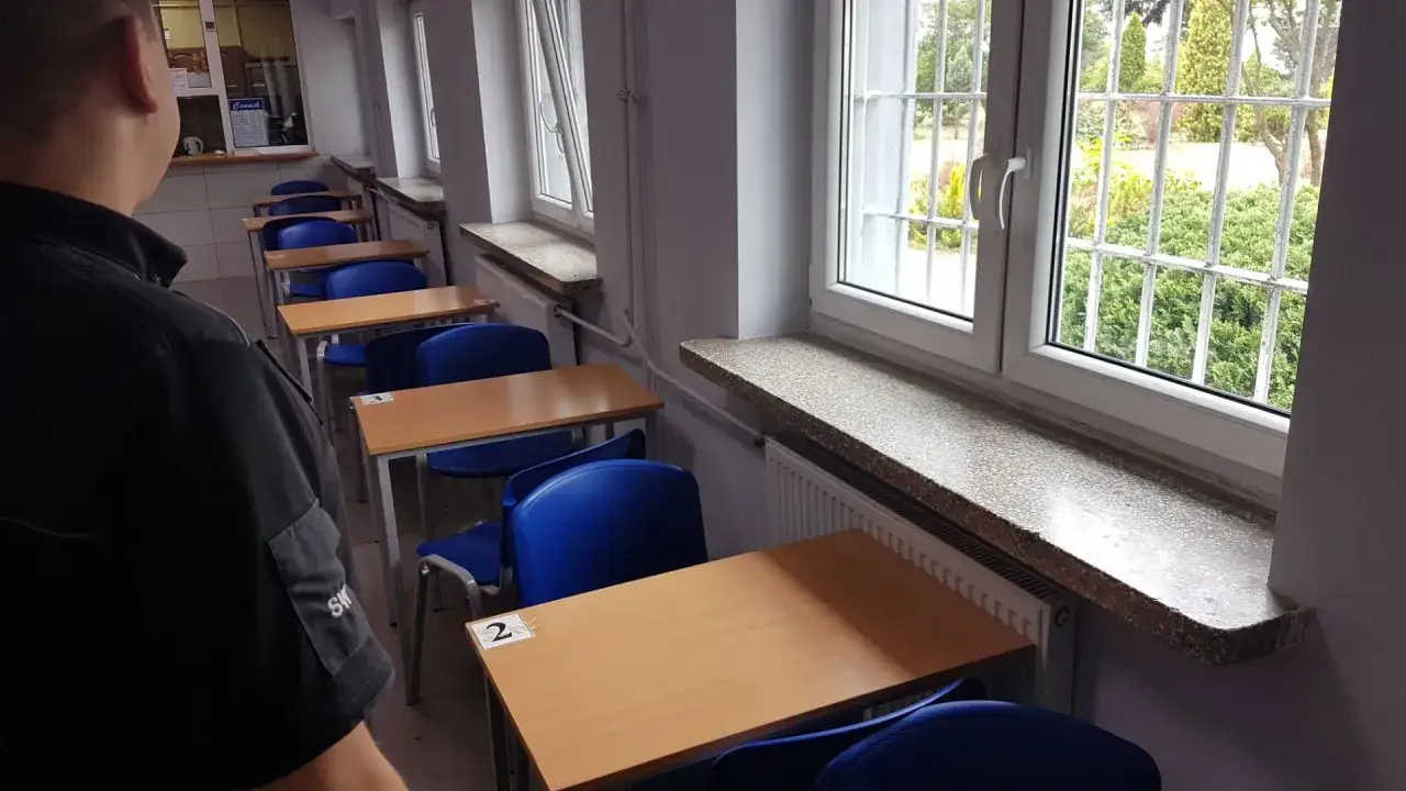 Pierwsze widzenie w areszcie śledczym. Puste ławki i niebieskie krzesła czekają na gości. Za kratami okien widać zieleń.