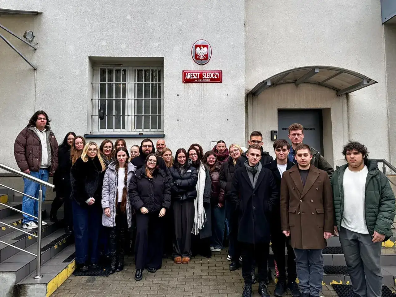 Grupa młodych ludzi przed budynkiem Aresztu Śledczego w Kielcach. Być może przyszli złożyć paczki dla bliskich.