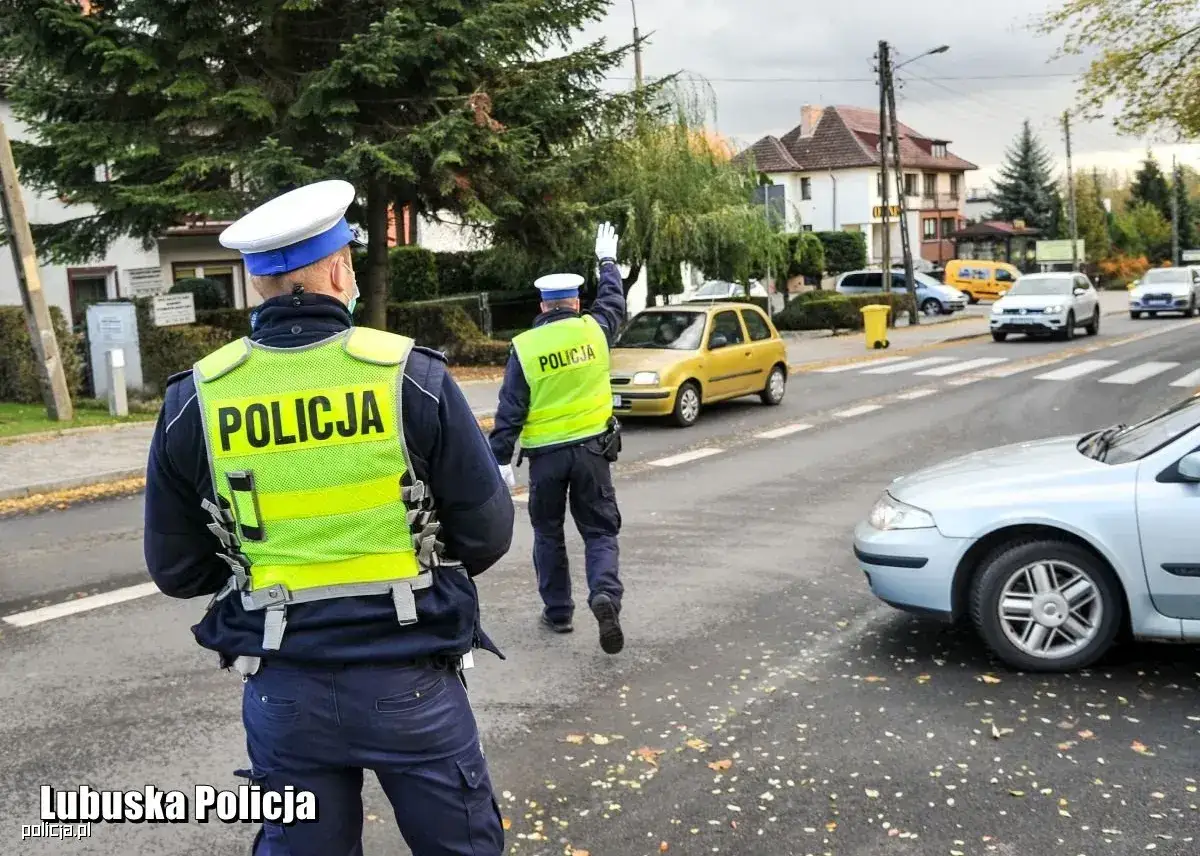 Policjanci kierują ruchem na skrzyżowaniu. Jeden z nich podnosi rękę, sygnalizując zatrzymanie pojazdów. Akcja ma na celu zapobieganie niebezpiecznym sytuacjom i potencjalnemu przepadek mienia.