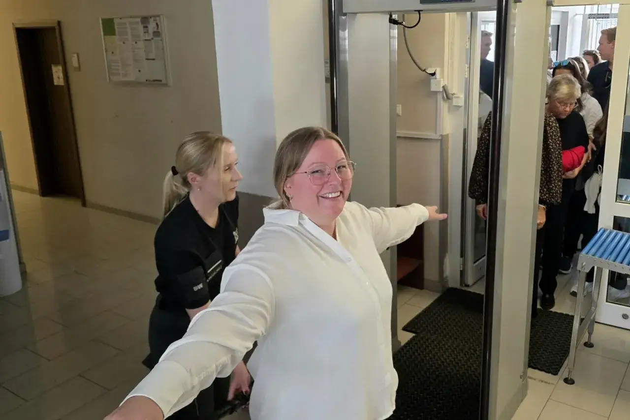 Kobieta przechodzi przez bramkę wykrywacza metalu, przygotowując się do widzenia w areszcie. Zastanawia się, co można zabrać na widzenie do aresztu.