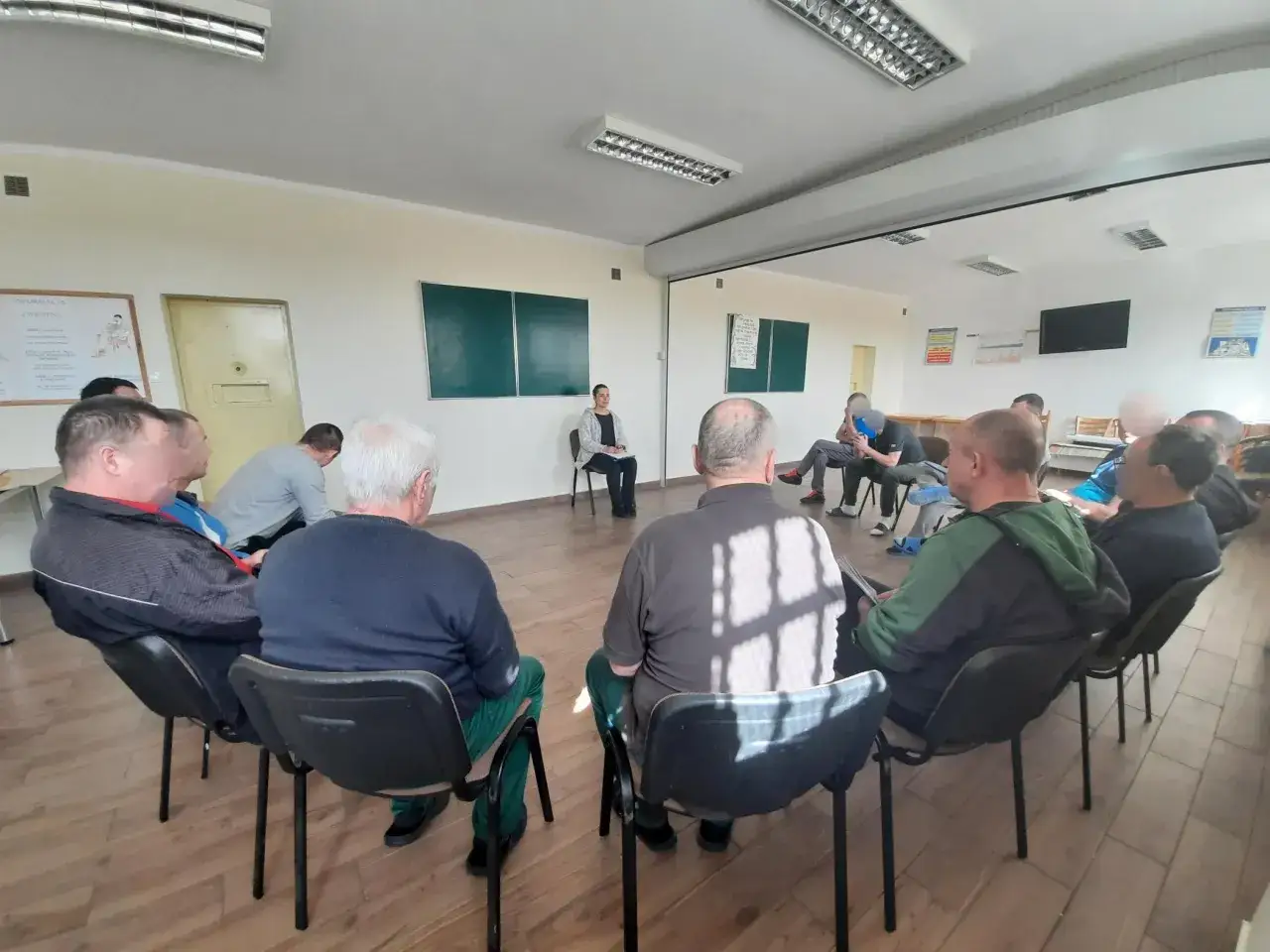 Grupa mężczyzn uczestniczy w sesji terapeutycznej, która jest częścią systemu terapeutycznego odbywania kary.