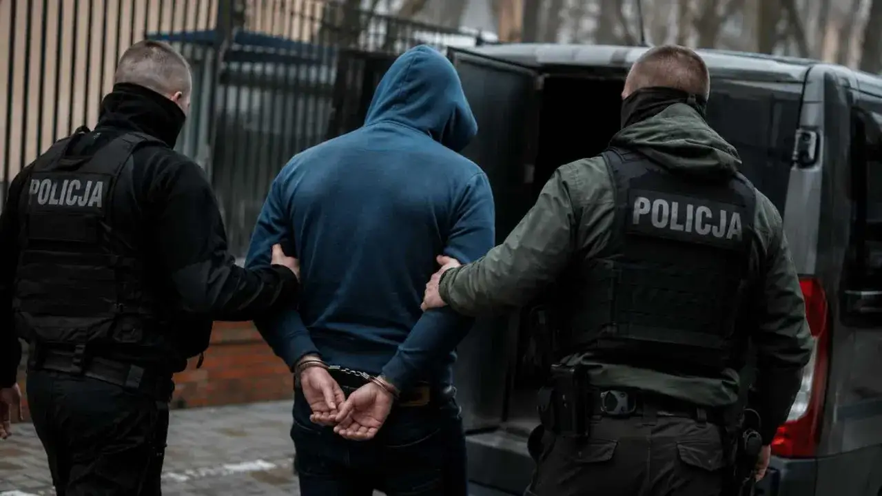 Policjanci zatrzymują mężczyznę w kajdankach. Podejrzenie o posiadanie narkotyków.