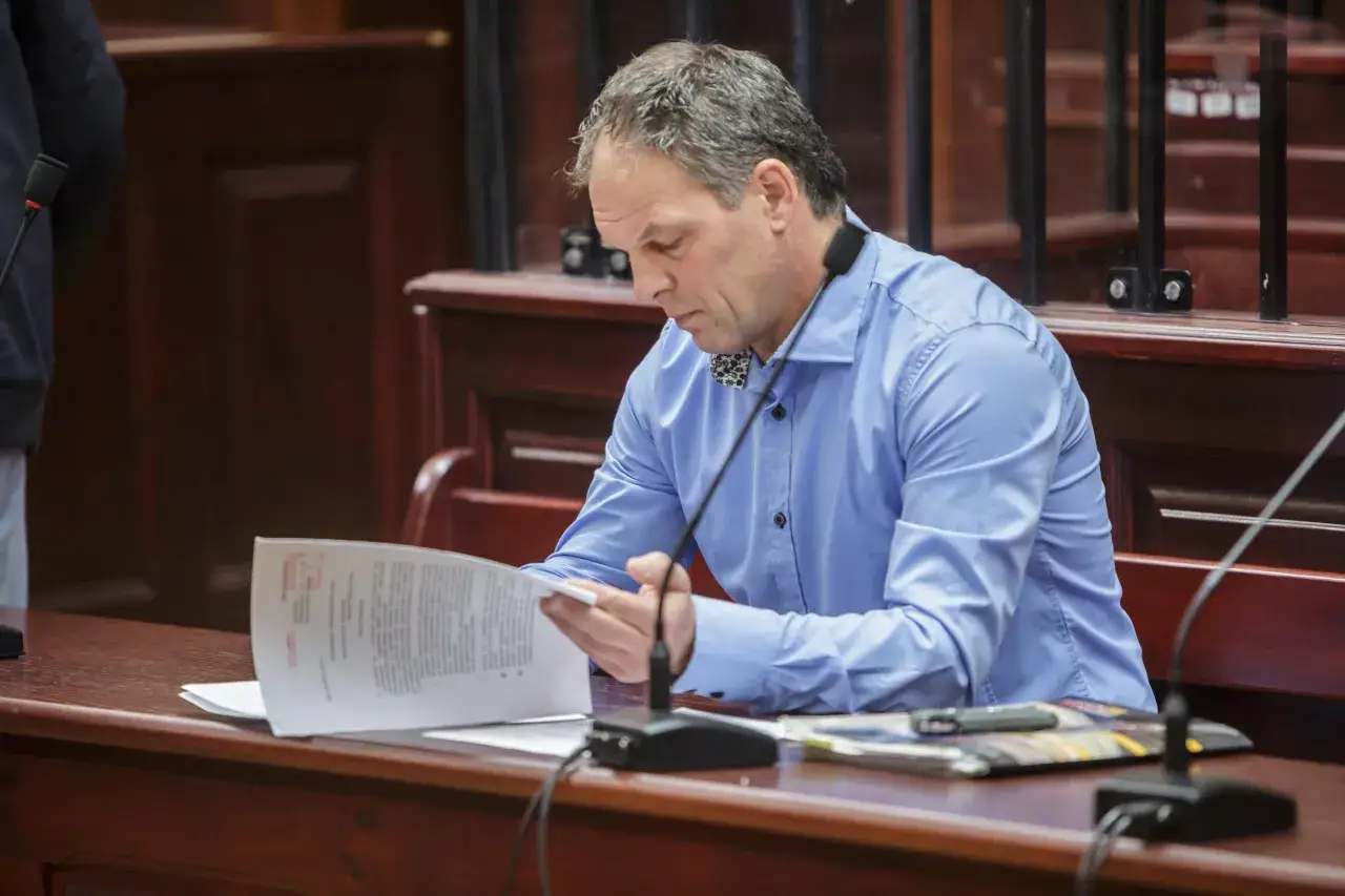 Mężczyzna w niebieskiej koszuli czyta dokumenty, zastanawiając się, co to jest nawiązka.