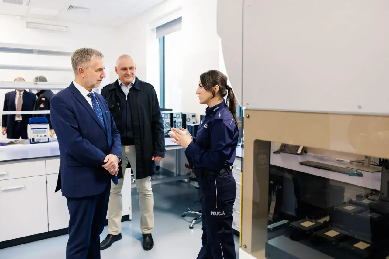 Policjantka wyjaśnia definicję środków odurzających dwóm mężczyznom w laboratorium kryminalistycznym.