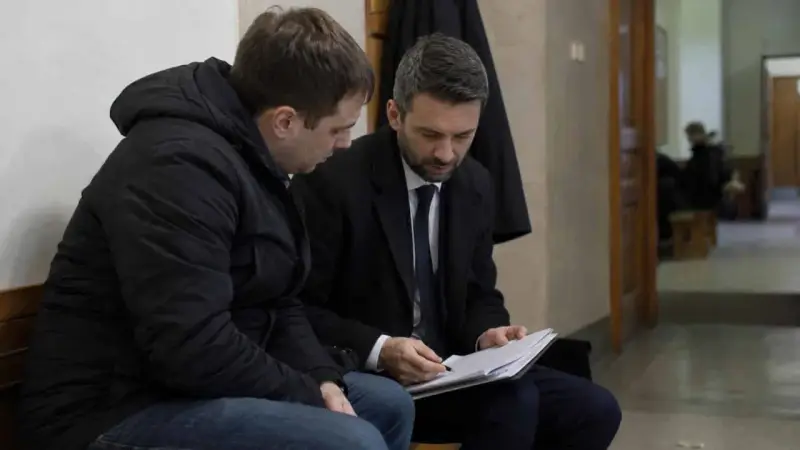 Prawnik omawia z klientem dokumenty dotyczące dobrowolnego poddania się karze a warunkowego umorzenia postępowania.